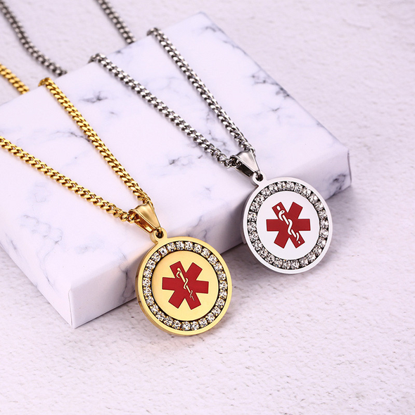 Unisex coin shaped silver and gold medical alert pendant necklaces with cubic zirconia stones displayed on marble stand.