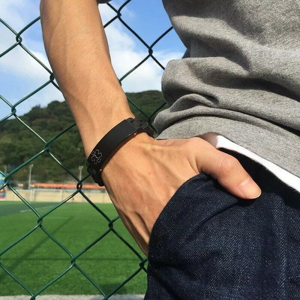 Man standing in front of a sports field wearing a Brooklyn black silicone medical alert bracelet.