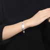 Lotus silver medical alert bangle on a female model's wrist wearing all black