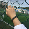 Titan X stainless steel medical alert bracelet on a male model at a sports field.